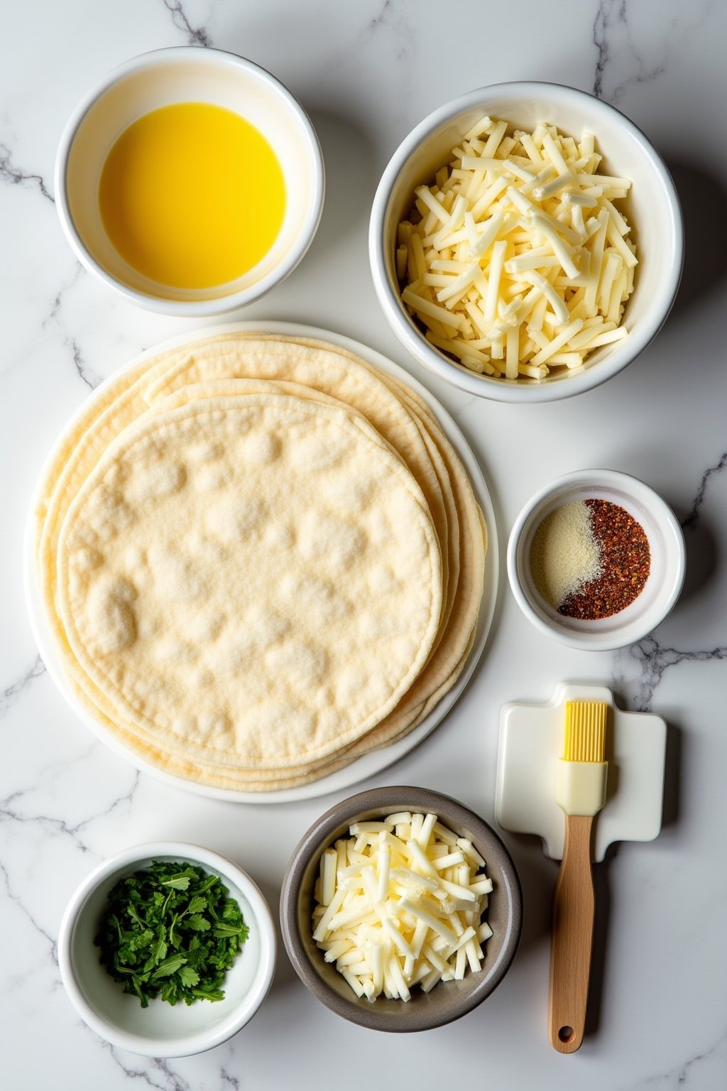 Overhead flat lay of cheesy tortilla garlic bread ingredients: large flour tortillas, a bowl of melted butter, minced garlic on a cutting board, shredded mozzarella in a bowl, grated parmesan, fres...